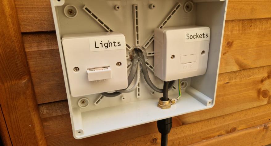 Weatherproof box with fused spurs for sockets and lights in a garden office